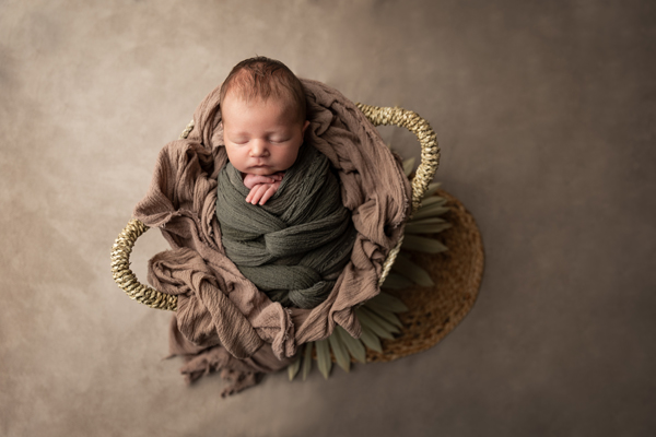 Baby in Flechtkorb gepuckt mit Blätter als Dekoration - Babyfotografie Reutlingen