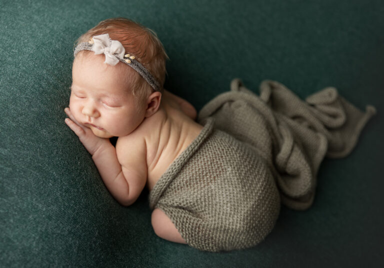 Baby auf grünem Hintergrund mit Wolltuch zugedeckt - Newborn Shooting bei Esslingen